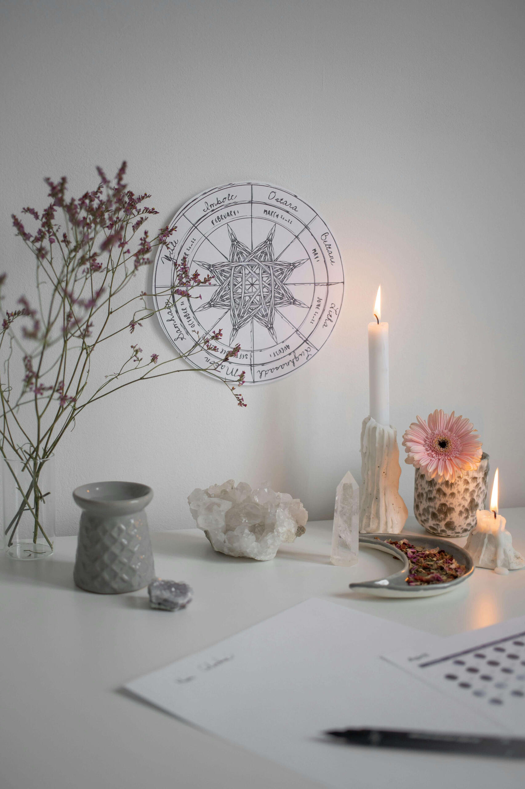 This is a photo of some crystals with the wheel of life and some flowers and candles